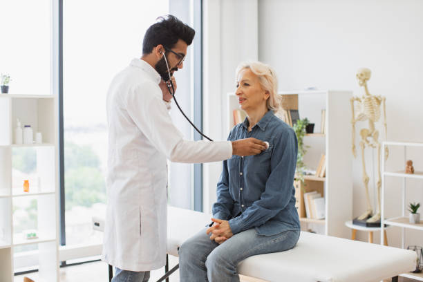 istock Adult man using stethoscope while elderly woman sitting on exam couch. 2148102263