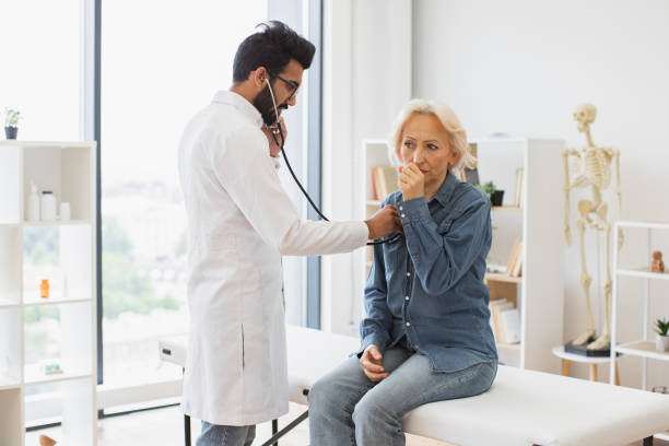 istock Bearded man in white lab coat checking lungs and heart via stethoscope. 2148102265