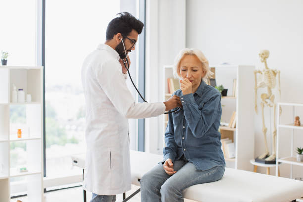 istock Bearded man in white lab coat checking lungs and heart via stethoscope. 2148102268