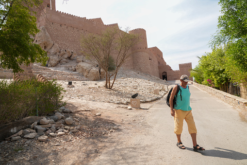 Men walking on sunny day  in front of the Nakhal Fort, in Oman . Is one of the oldest and biggest forts in Oman, inscribed on the UNESCO World Heritage List