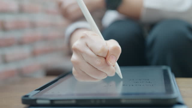 A person is writing on a tablet with a pen