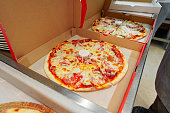 Two Freshly Baked Pizzas in Open Cardboard Boxes Ready for Delivery