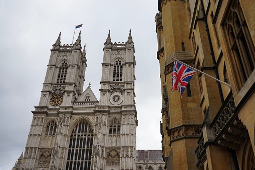Clean picture of Westminster Abbey, with a Union Jack in the foreground, on a cloudy day in London, United Kingdom