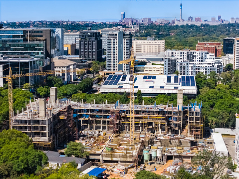 Johannesburg, South Africa - April 9, 2024: New building construction in Rosebank, a cosmopolitan commercial and residential suburb to the north of Johannesburg city centre (seen on the horizon) and is the location of a Gautrain station.