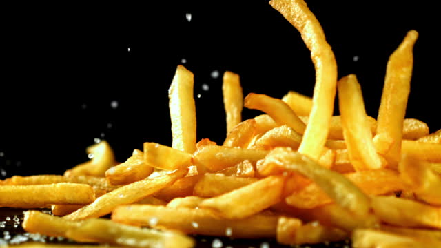 Super slow motion French fries are deep-fried in oil