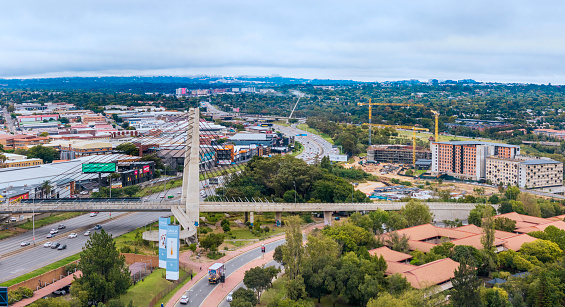 Johannesburg, South Africa - April 8, 2024:  New building apartment construction in Sandton City with Wynberg industrial site seen over the M1 highway and the pedestrian bridge over the highway.