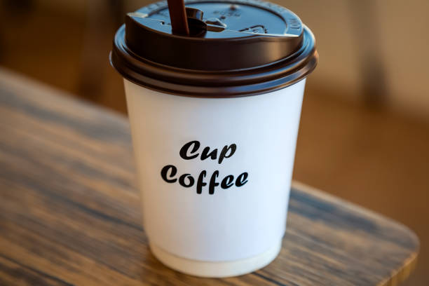 A Paper Cup of Hot Coffee with Plastic Cap Placed on the Table