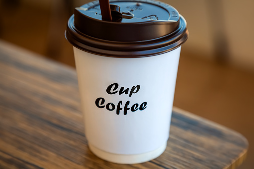 A Paper Cup of Hot Coffee with Plastic Cap Placed on the Table