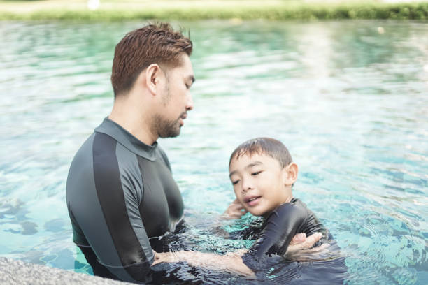 istock Man teaching boy to swim in the pool 2148111909