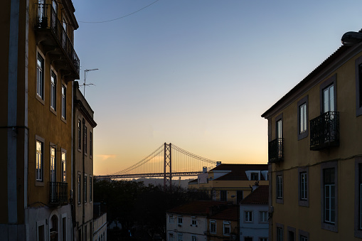 25 de Abril bridge seen from between the buildings in sunset