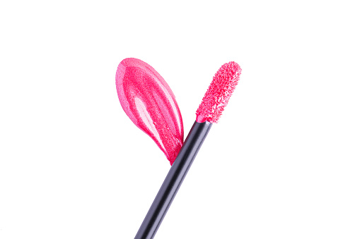 Pink shiny liquid lipstick and applicator isolated on white background. Swatch of deep pink lip gloss. Top view, flat lay, copy space
