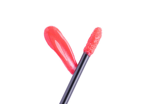 Red liquid lipstick and applicator isolated on white background. Swatch of red lip gloss. Top view, flat lay, copy space