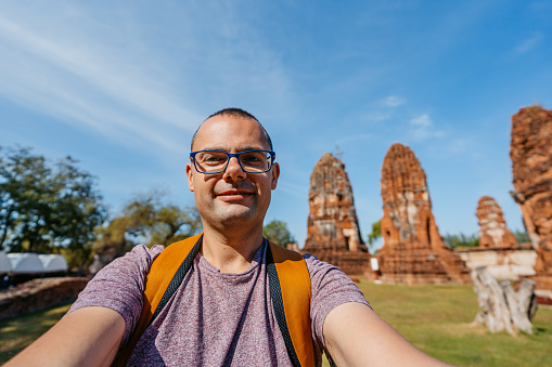 Young man taking selfies using smart phone at Wat Mahathat in Ayutthaya in Thailand.