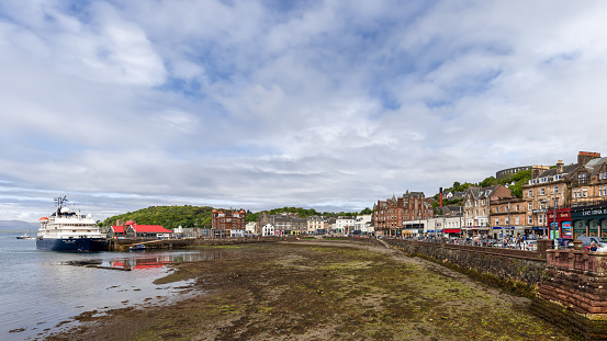 Oban - United Kingdom. May 21, 2023: The bustling resort town of Oban unfurls along the shore, as a cruise ship and local boats idle in the calm bay