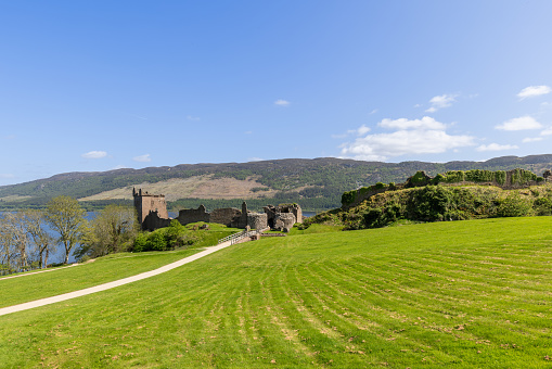 Drumnadrochit - United Kingdom. May 25, 2023: The historic ruins of Urquhart Castle offer a panoramic view over Loch Ness, with a pathway leading through vibrant green landscapes