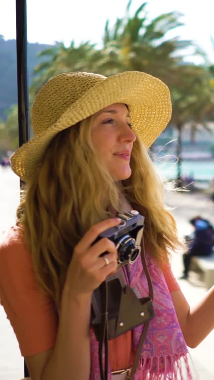 A young woman wearing straw hat enjoying traveling on an old tram or train along sea coast. A vertical video.