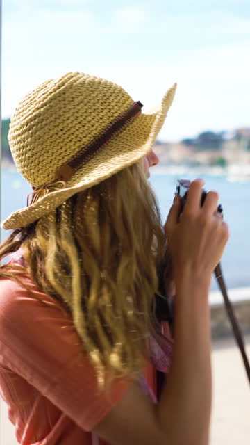 A young woman wearing straw hat enjoying traveling on an old tram or train along sea coast. A vertical video.