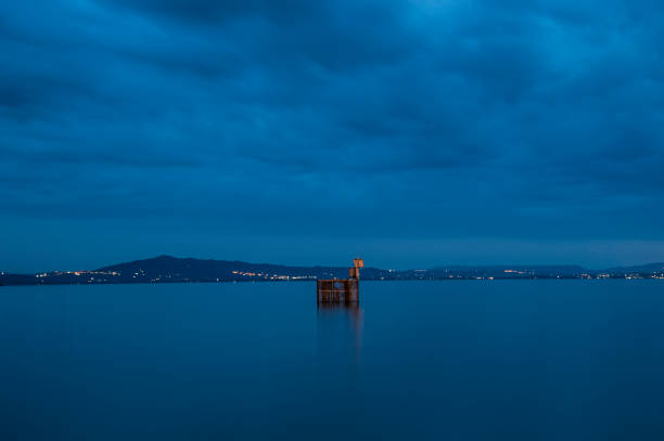 Trasimeno lake minimal long exposure at blue hour in a cloudy day, sooting landscape, tranquil scene in Umbria region