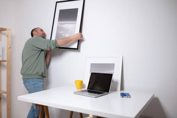 istock Man hanging pictures on the wall. 2148115400