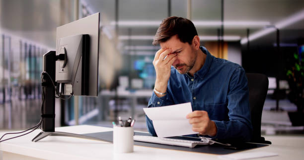 istock Shocked Young Businessman Reading Document At Desk 2148115676