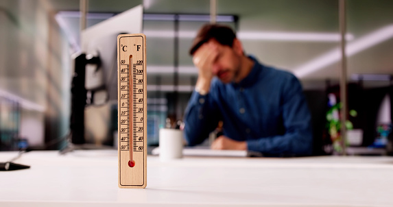 Thermometer In Front Of Businessman Working During Hot Weather In The Office