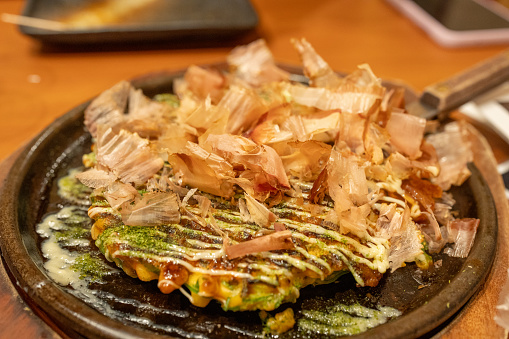 A close up photograph showing a plate of Okonomiyaki