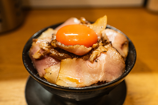 A bowl of Japanese char-siu rice served with a raw egg yolk