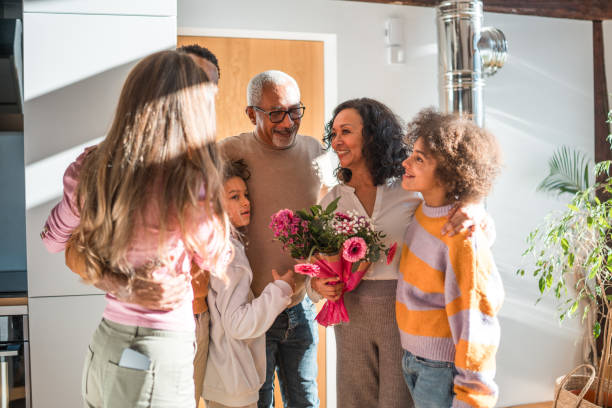Vibrant autumn mums in a vase on a wooden surface with a person's feet. The warm tones of the autumnal flowers and wood create a cozy and inviting home atmosphere. Congratulations, floral present gift