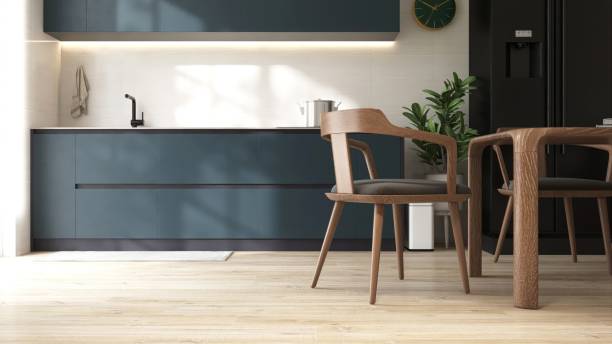 istock Light brown laminated parquet floor of modern dining room, kitchen with wooden table and chairs, dark teal blue counter cabinet, cupboard and refrigerator in sunlight 2148118352