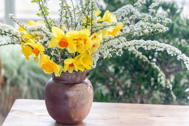 Still life with daffodil flowers in vase on table with blurred background.