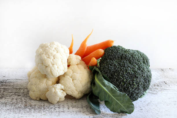 Fresh broccoli, carrot and cauliflower on wooden table, white background. Healthy and vegetarian food. Copy space.