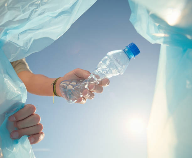 Plastic, bottle and hands for cleaning, volunteering or helping with climate change, pollution or environment. People closeup with recycling bag and plastic for social responsibility in a low angle