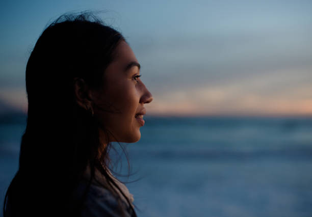 Woman, profile and sunset by ocean with smile, space or thinking with memory for mockup on vacation. Person, girl and happy with ideas in wind by water, beach and sea for tropical holiday in Jakarta