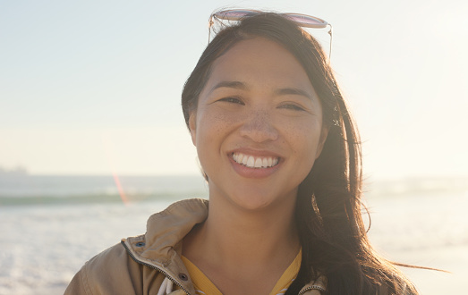 Happy, portrait and beach with asian woman on vacation, summer holiday or outdoor weekend in nature. Face of female person with smile on tropical island for adventure by the ocean coast or shore