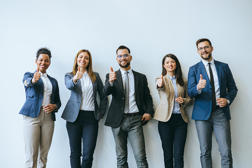 Positively minded business team members are giving thumbs up in a show of approval within an office setting