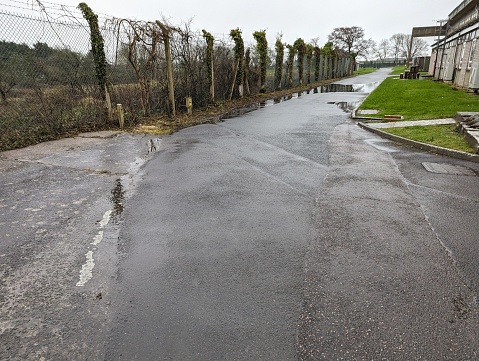 This empty, wet road stretches beside buildings, capturing the bleak atmosphere of rainy South Wales, a scene familiar to any local survey team