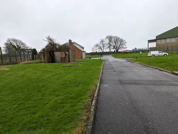 Photo of Wet roadway near a small building and trees