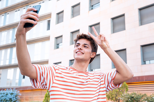 A happy student is inside the university campus taking a self-portrait with a cell phone. College life