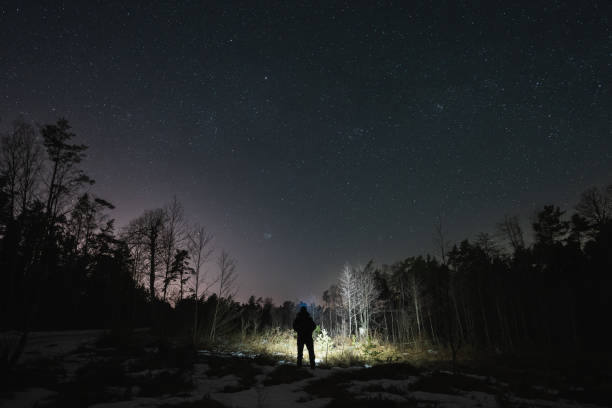 istock Night scene, a man with a flashlight in a dark forest in winter. 2148123547