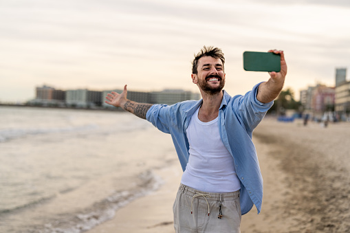 Happy tourist taking self portrait outside with cellphone on summer vacation