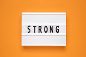 The word strong on lightbox isolated orange background.