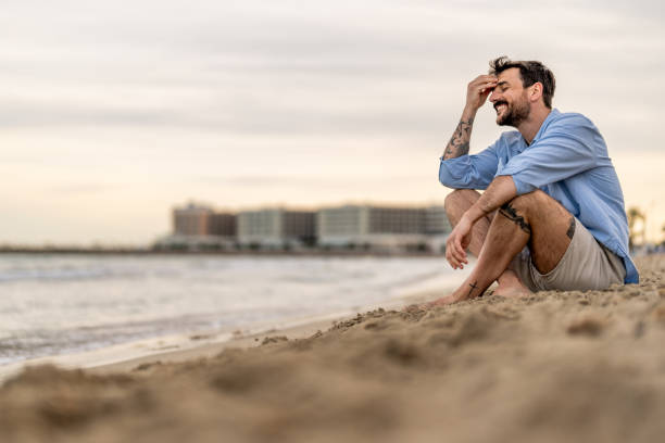 Bearded Man relaxing alone on the seaside on hot sunny day at sunset.