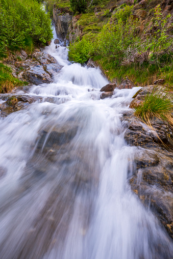 Stream coming down the mountain in the Venter tal in the Ötztal valley in Tyrol Austria during a beautiful springtime day in the Alps. Long exposure photo with smooth waterfall.