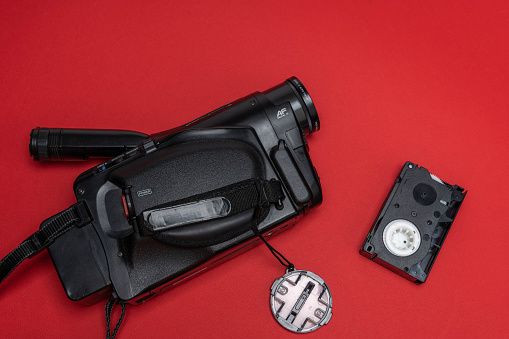 Vintage VHS video camera and a cassette with home video film on a red background. retro, 90s