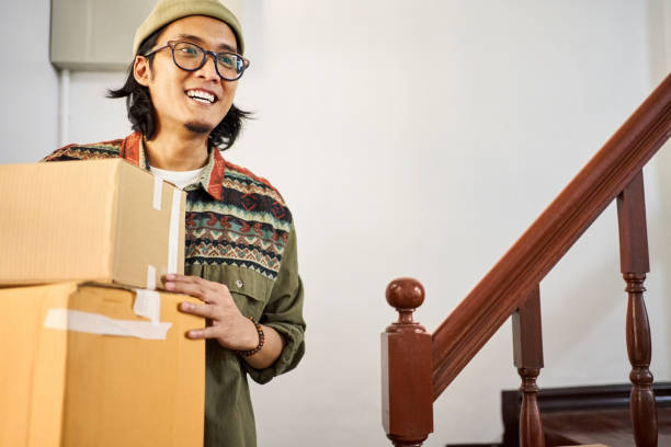 Happy young man carrying boxes moving to a new apartment