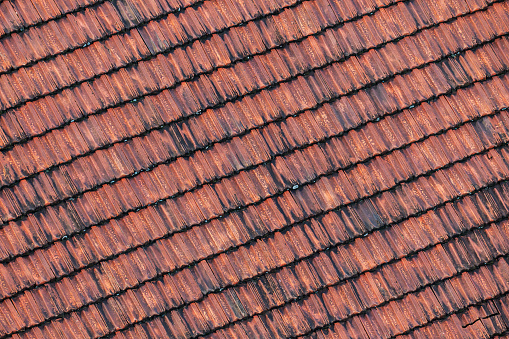 Close up of weathered rusty red tiles on roof of medieval building for textured background
