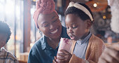 Mother, child and milkshake, relax in restaurant for dinner and drinks, young girl and woman with enjoyment. Happiness, dessert or shake with black family in diner, love and bonding with beverage