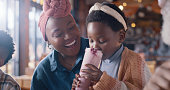 Mom, kid and milkshake, relax in restaurant for dinner and drinks, young girl and woman with enjoyment. Happiness, dessert or shake with black family in diner, love and bonding with icecream beverage