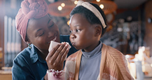 istock Help, face and mother with kid in restaurant for lunch, drinks and bonding together in diner. Food, strawberry milkshake and black woman with girl child in cafe for dinner, mom and daughter at table. 2148128059