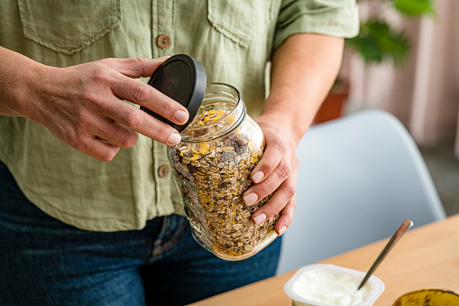 Woman using recycled glass jar to storage dried food. High resolution 42Mp studio digital capture taken with Sony A7rII and Sony FE 90mm f2.8 macro G OSS lens